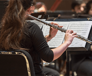 Female student playing a flute and reading sheet music