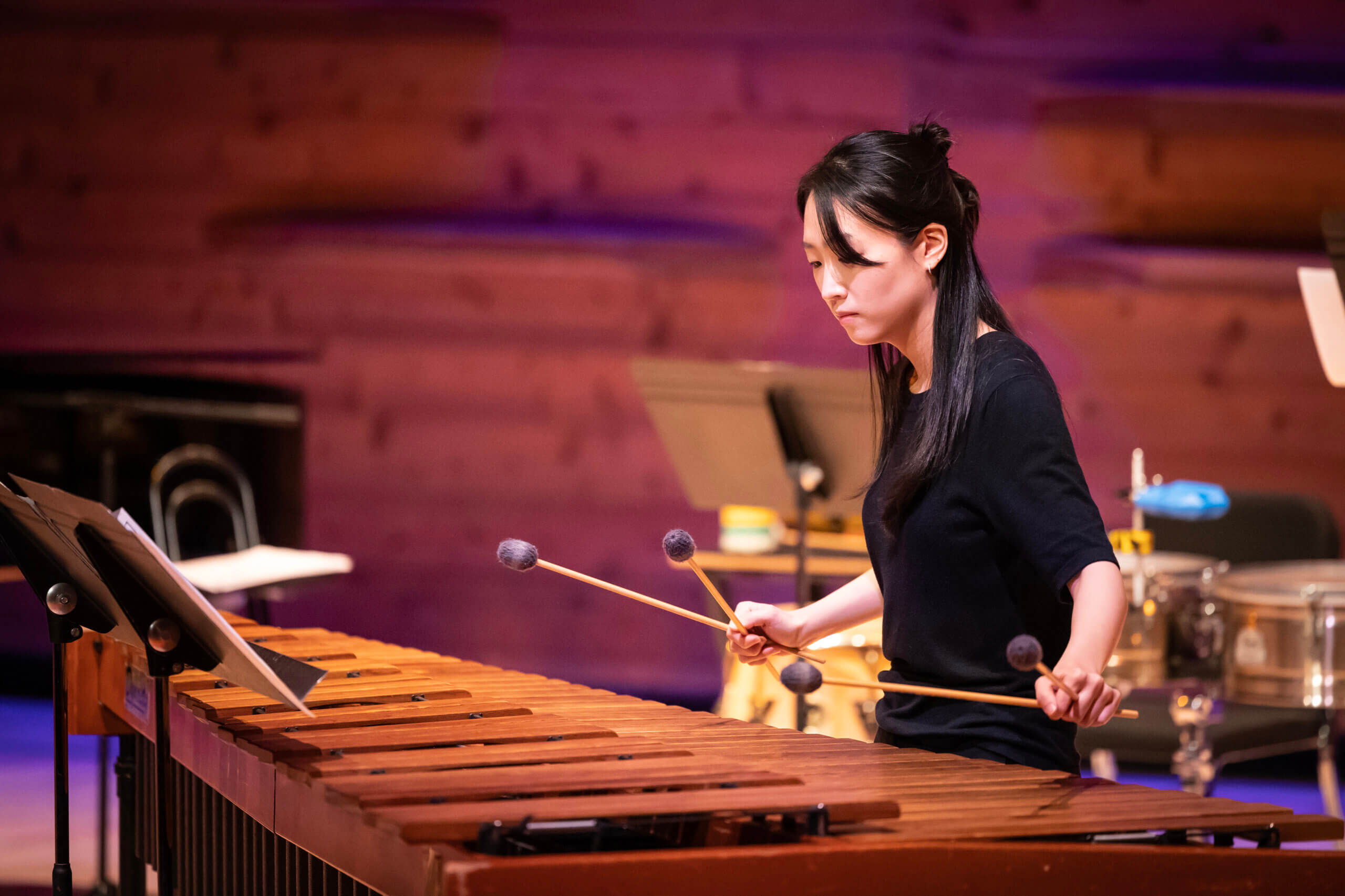 A student performs a percussion instrument on stage.