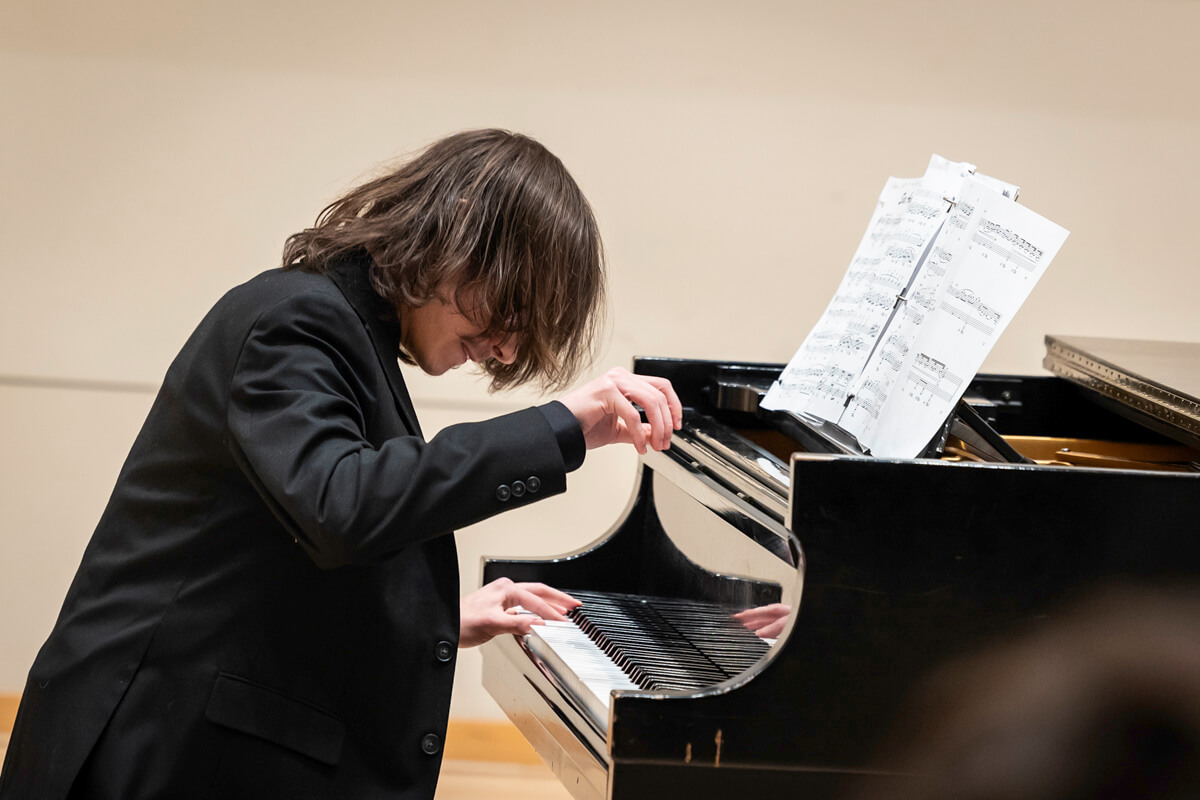 Musician plays a piano with sheet music on the piano.