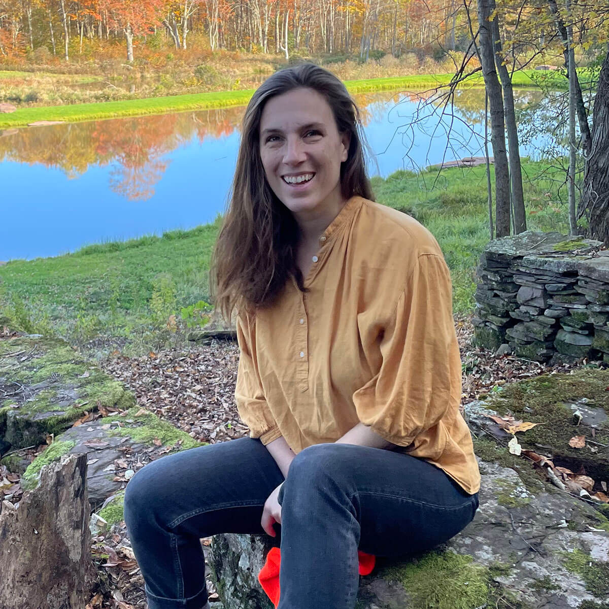 Woman sitting near a lake.